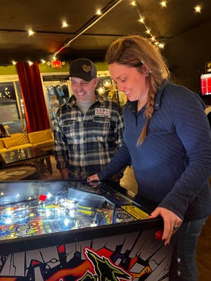 Amanda Conrad plays pinball while her husband, Andy, looks on at the arcade next to Sandy Springs Brewing Co. in Minerva. The arcade was added to the couple's brewery business late last year.